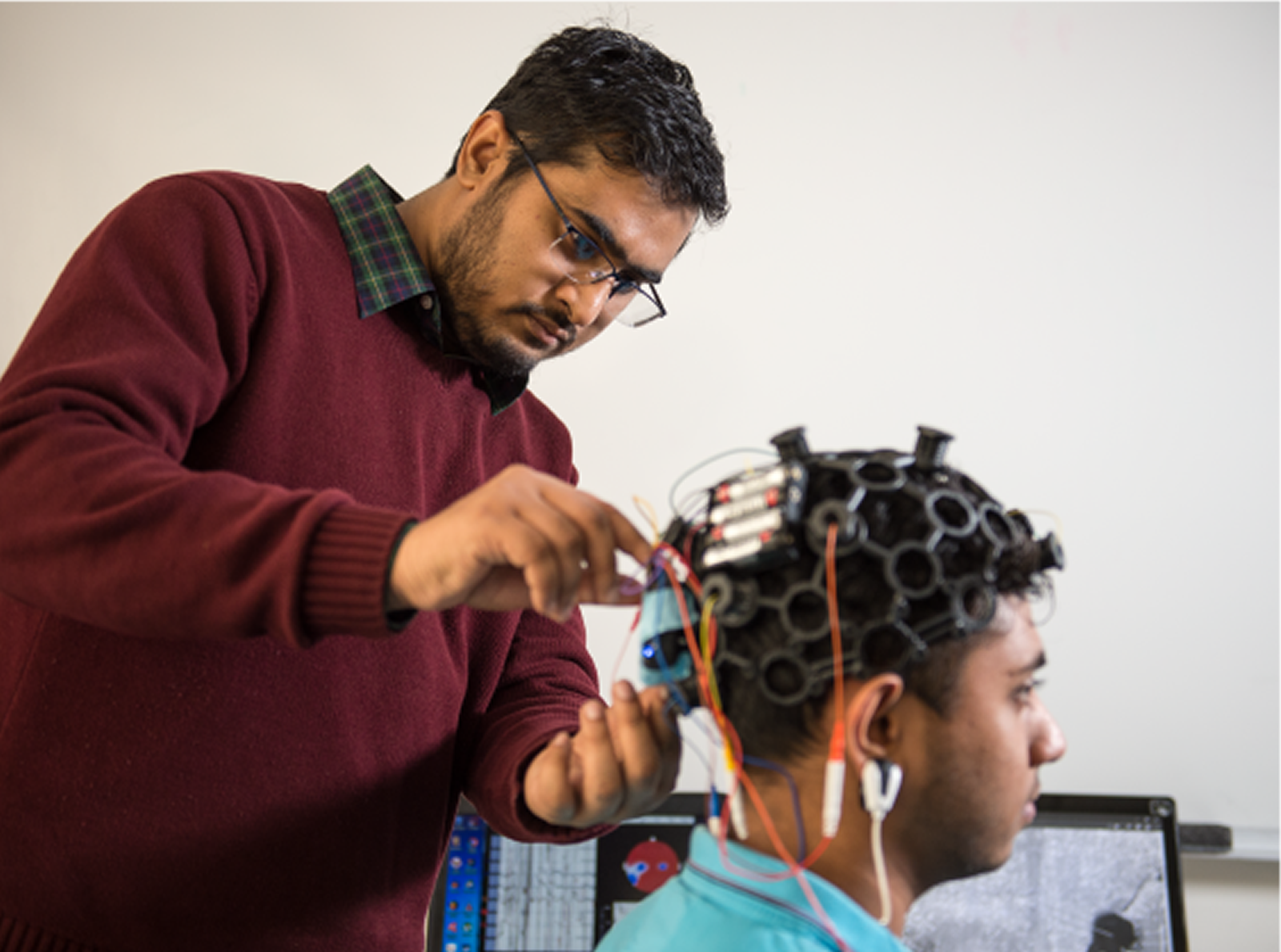 Faculty member adjusting sensors on brain mapping head piece